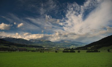 Çayırlar, tepeler ve dağlar Mautendorf Köyü, Avusturya yakınındaki günbatımı sırasında güzel bir manzaraya.