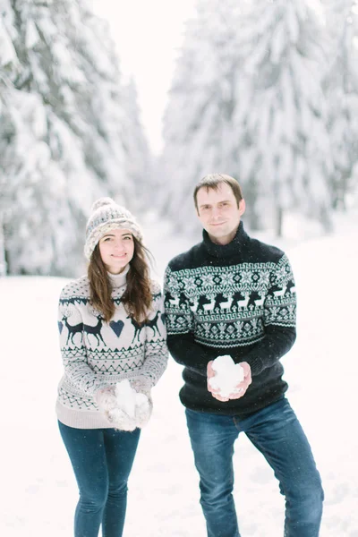 Young happy couple playing with snow in white winter forest