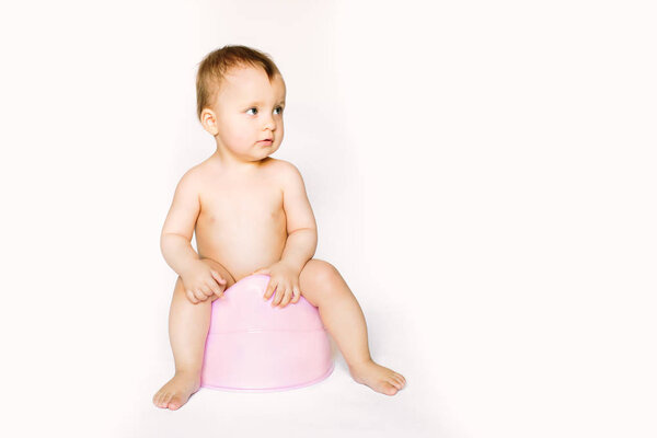 Infant child baby girl toddler sitting on potty toilet stool pot isolated on a white background.