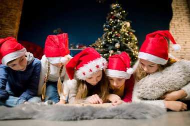 Rahat oda katta ve arka plan bir Noel ağacı ve yazma harfleri Santa için yalan küçük güzel çocuk.