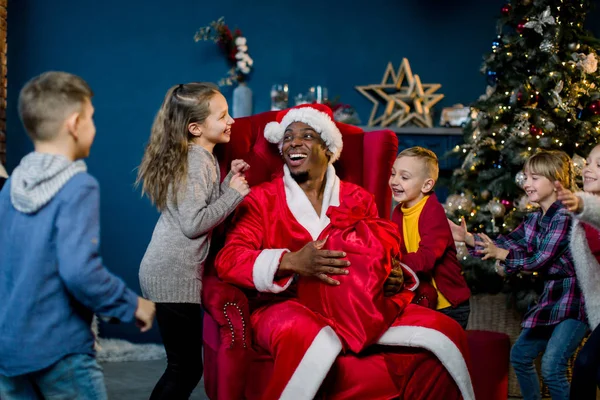 アフリカのサンタ クロースとクリスマス ツリーの背景に小さな子供たち幸せ — ストック写真