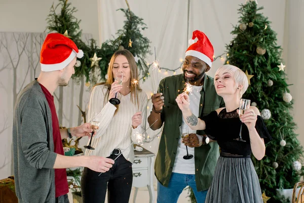 クリスマス パーティーでシャンパンとベンガルの火災のメガネを楽しんで友人の幸せな国際グループ — ストック写真