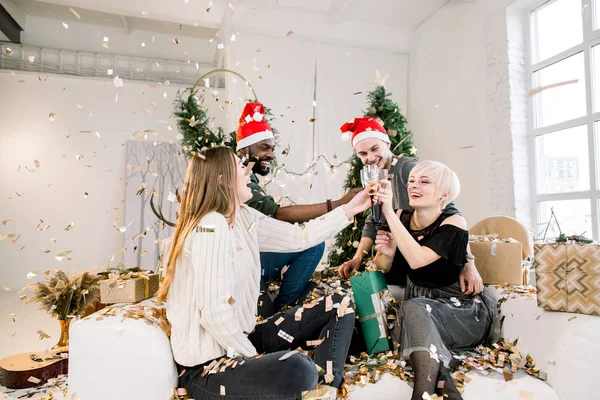 お正月とクリスマスのお祝いのコンセプトです シャンパンと金色の紙吹雪を投げるを飲んで楽しんで若いの多民族の友人のグループ — ストック写真