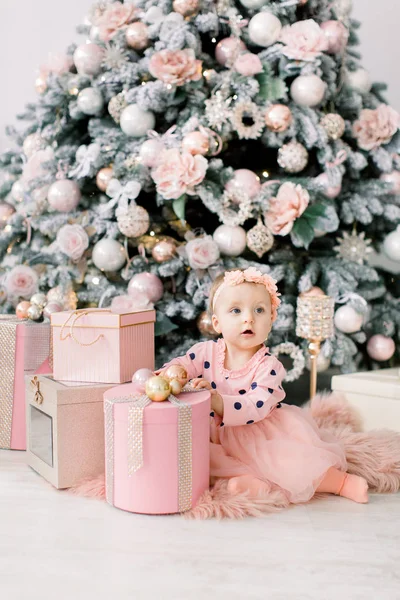 Bklom でかわいい女の子は小麦粉に座っているドレスし 背景クリスマス ツリーのプレゼントのボックスを開きます クリスマス休暇の概念 — ストック写真