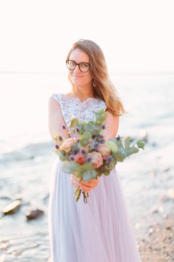 Genç ve güzel kadın zarif mavi elbise gülümseyen ve buket çiçek tutan, Garda Gölü yürümek. Sirmione, İtalya.