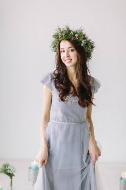 Güzel genç kız gri Abiye ve çam ve okaliptüs düğün sahne arka plan üzerinde kafa onun pozlar üzerinde bir çelenk. Daha önce düğün Studio Bridesmade pozlar.