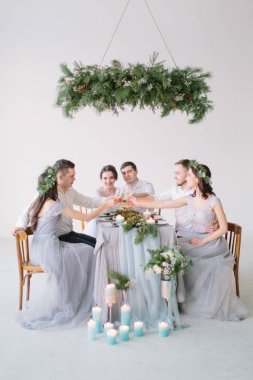 Grup insanlar gelin ve damat, nedime ve düğün pastası, çam dekorasyon ve mum beyaz düğün masada oturan groommen salonu dekore edilmiştir.