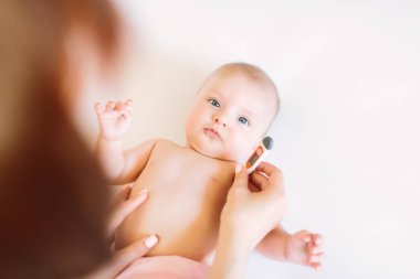 Termometre hasta bebeği tutan anne. Hasta bebek yatakta ateşli Sıcaklığı ölçme