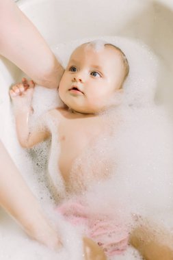 Mutlu gülen Bebek banyo köpük kabarcıkları ile oynarken. Küçük çocuk bir küvet içinde. Bebek yıkama ve banyo. Hijyen ve genç çocuklar için bakım. Yeni doğan bebek banyo