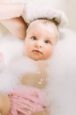 Mutlu gülen Bebek banyo köpük kabarcıkları ile oynarken. Küçük çocuk bir küvet içinde. Bebek yıkama ve banyo. Hijyen ve genç çocuklar için bakım. Çok güzel banyo bebek sabun köpük saç ile