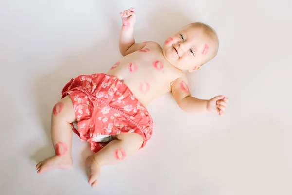 Image of adorable child with red kisses on the skin, happy baby boy sitting down in the studio and isolated on white background, little love angel, romantic holiday, Valentines day concept