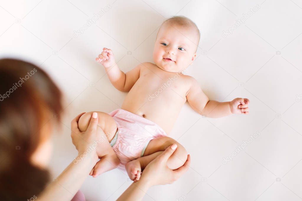 Baby massage. Mother massaging and doing gymnastic with legs of her kid