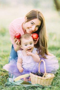 Anne ve çocuk bebek kız çiçeklenme içinde meyve ile oynamaktan bahar bahçe mutlu. Anneler günü tatil kavramı