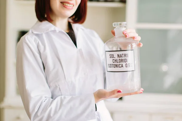 Pharmacist in lab holding glass bottle with natrium chloride