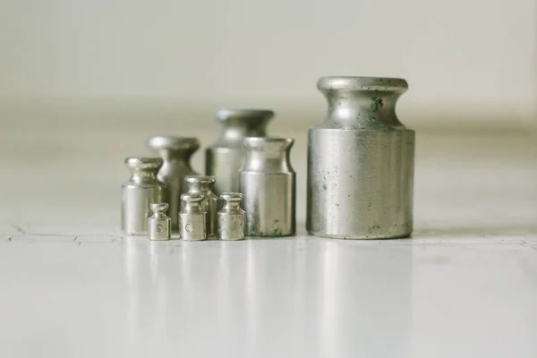 Set of pharmacy laboratory precision weights for a balance scale on an old table