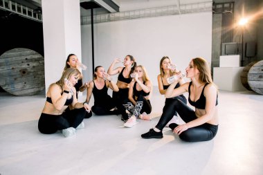 Fitness spor salonu Studio sonra zemin ve içme suyu üzerinde oturan siyah giysili güzel fitness kadınlar