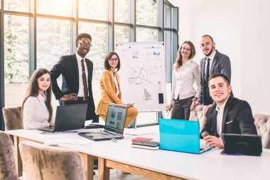 İş adamları istatistikleri sunum bir binanın içinde yapıyor. Büyük takımın bir parçası olduğum için mutluyum. Kameraya bakarak ve gülümseyen iş adamları grubu