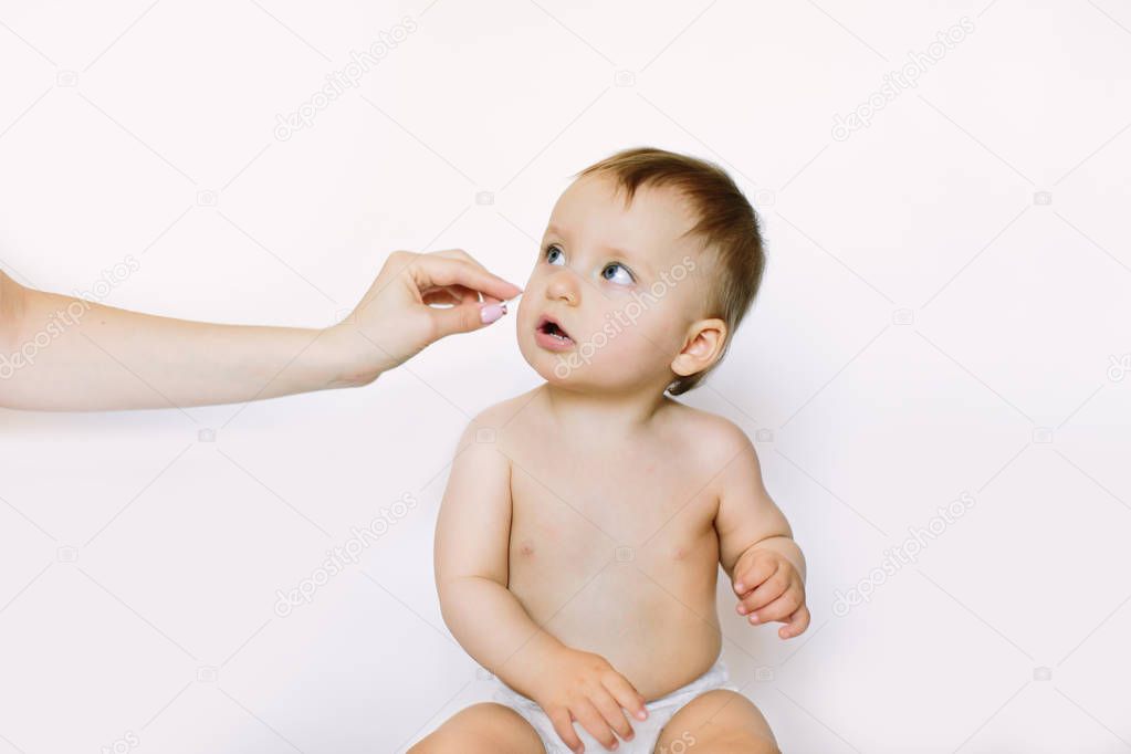 closeup Portrait baby. Mother cleaning her baby ears with cotton swab, isolated on white background. Newborn hygiene. concept cleaning wipe, pure, clean.