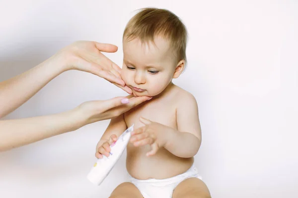 Mulher Aplicando Creme Corporal Seu Bebê Contra Fundo Claro — Fotografia de Stock