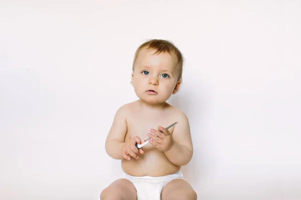 A baby girl uses a thermometer, holds it in her hands on a white background