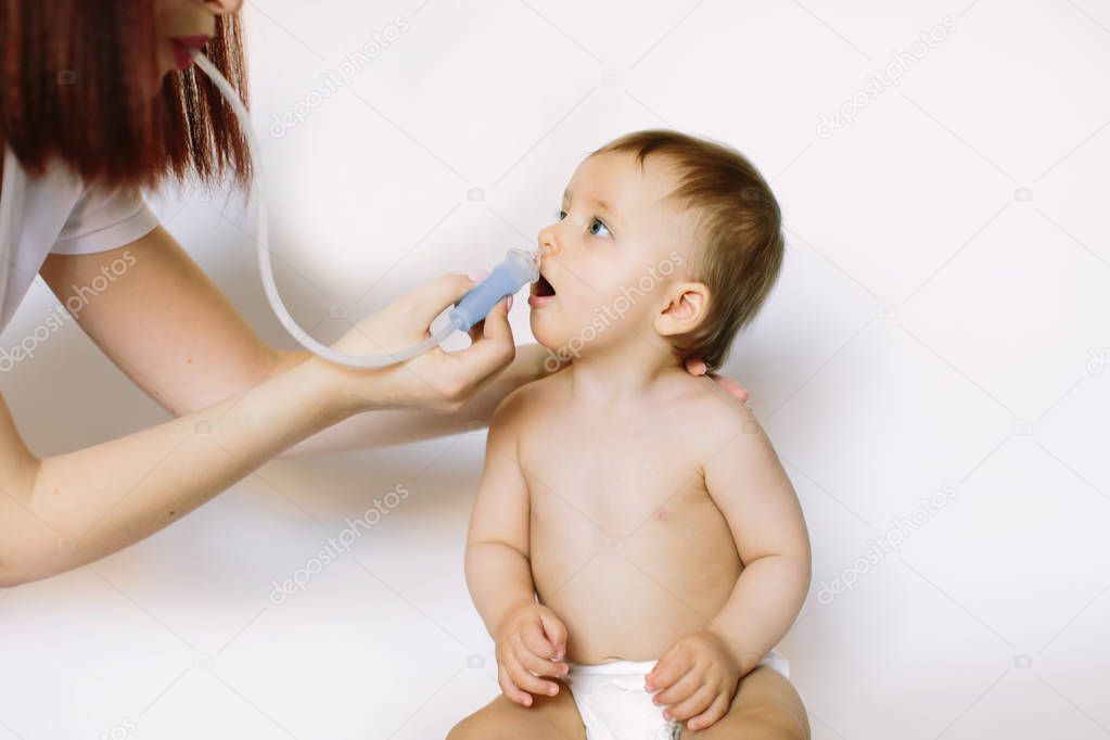 Mother using nasal aspirator for cute little baby on white background. Health care concept