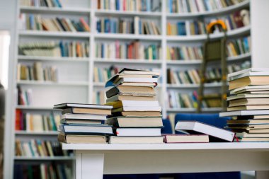 Kütüphanede kitap yığını ve kitaplık arka plan bulanıklık