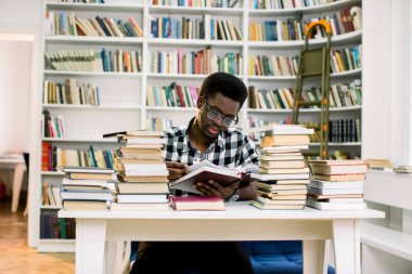 endişeli Afrika öğrenci Danışma kitaplığındaki kitap bakarak