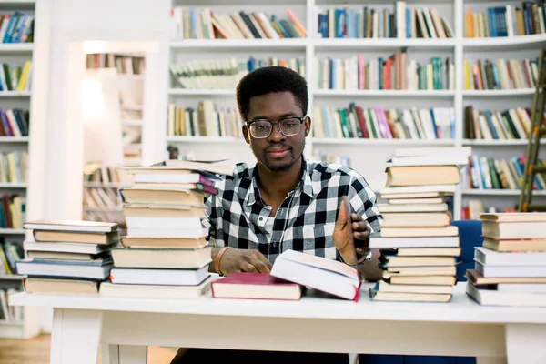 民族アフリカ系アメリカ人の男は図書館にある本に囲まれたテーブルで座っています 学生は本を読んでください — ストック写真