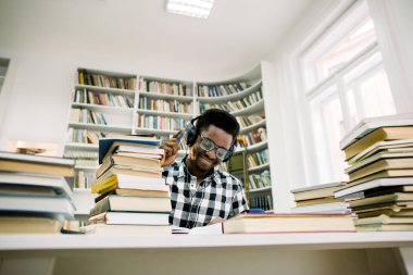 Güzel, esmer öğrenci öğrenci kulaklık ile bilimsel literatür, kalemle notlar yapma okur
