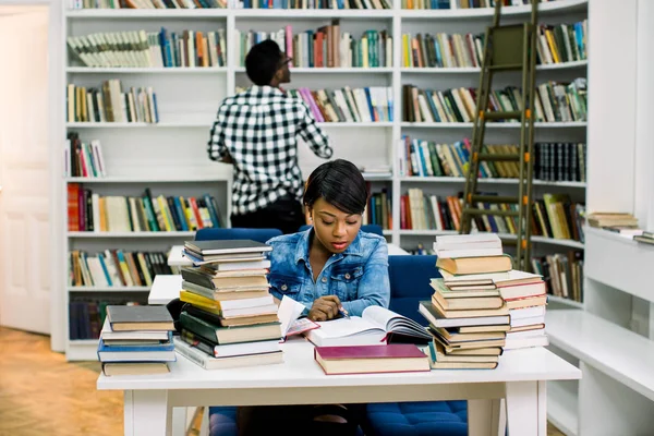Mujer Joven Afroamericana Leyendo Libro Texto Sentado Mesa Fondo Estantería —  Fotos de Stock