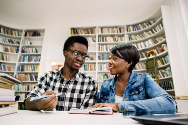 Afrika kökenli Amerikalı öğrenciler kitaplığında inceliyorlar. Gençler birlikte vakit. Çekici kadın ve yakışıklı erkekler birlikte çalışıyoruz.