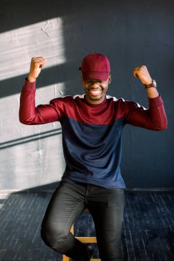 Uzanmış ve gülerek silah ile heyecanlı genç Afrika adam portresi bir kırmızı yün kazak ve kırmızı şapka giymiş