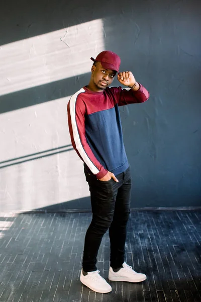 kırmızı yün kazak ve kırmızı kap stüdyoda bir Afrikalı-Amerikalı hipster biri şık Afro guyportrait giymiş. Karanlık dokulu arka plan öğrenci spor giyim üzerinde izole