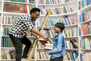 Rahat kıyafetler onun Afro-Amerikan kız öğrenci Kitaplığı'nda adım merdiven üzerinde dururken gerekli bir kitap verilmesi yararlı genç Afro-Amerikan öğrenci