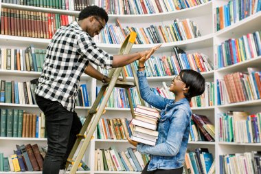 Rahat kıyafetler onun Afro-Amerikan kız öğrenci Kitaplığı'nda adım merdiven üzerinde dururken gerekli bir kitap verilmesi yararlı genç Afro-Amerikan öğrenci