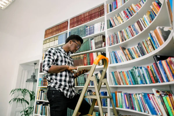 Estudiante Afro Americano Relajado Reflexivo Ropa Casual Estando Biblioteca Leyendo —  Fotos de Stock