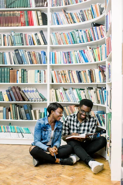 Gelukkige Jonge Afro Amerikaanse Paar Zittend Een Vloer Bij Boekenkast — Stockfoto