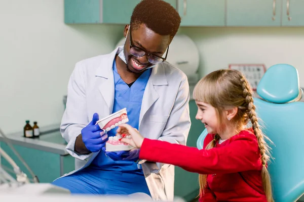 Африканский Стоматолог Показывает Чистить Зубы Маленькой Белой Девушке Пациентке Используя — стоковое фото