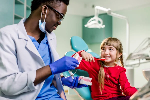 Menina Está Sentada Cadeira Dentária Sorrindo Para Dentista Afro Americano — Fotografia de Stock