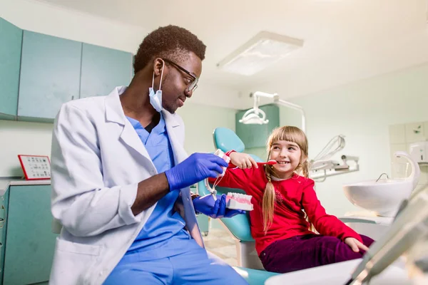Menina Está Sentada Cadeira Dentária Sorrindo Para Dentista Afro Americano — Fotografia de Stock