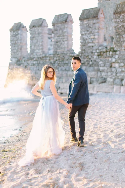 young charming couple in luxury clothes walking together near the Garda lake in Sirmione. Love in Italy