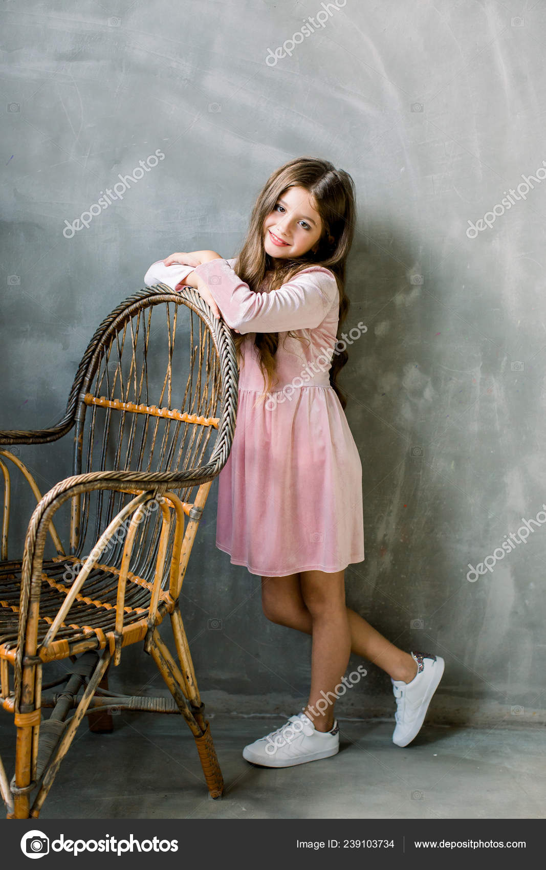 Linda niña de 5-6 años con elegante vestido rosa sentado en la