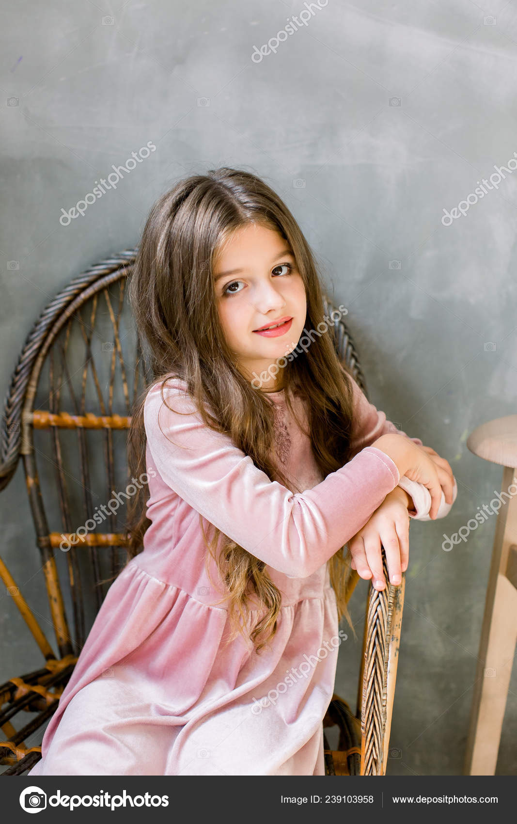 Linda niña de 5-6 años con elegante vestido rosa sobre fondo gris. mirando  a la cámara fiesta de cumpleaños. celebracion.