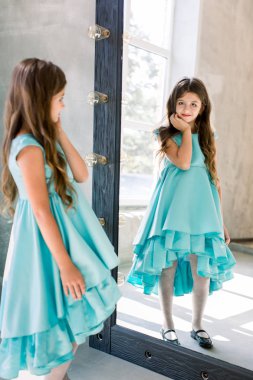 Aynaya bakıyor güzel küçük kız güzel mavi elbiseyle poz poz