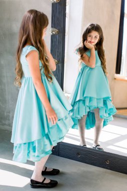 Aynaya bakıyor güzel küçük kız güzel mavi elbiseyle poz poz