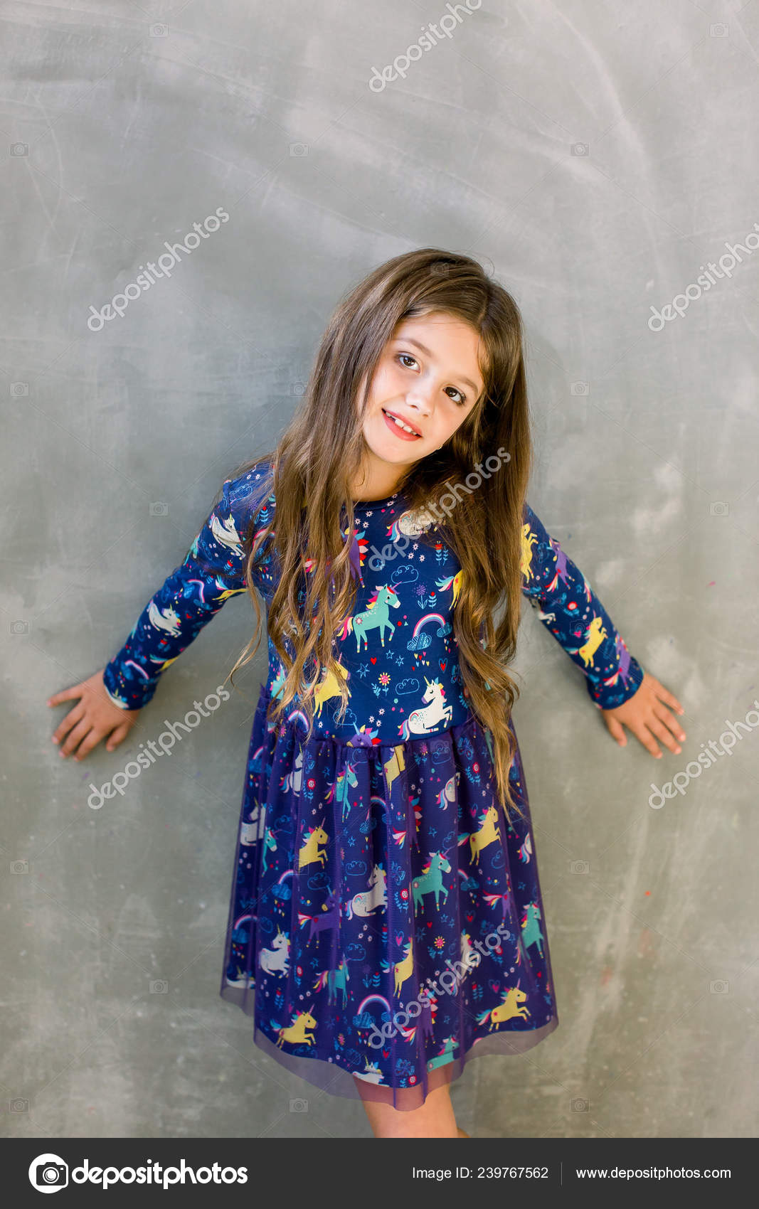 Linda niña de 5-6 años con elegante vestido rosa sobre fondo gris