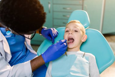 Küçük boy gülümseyerek diş kontrol koşulu Afro-Amerikan etnik siyah erkek dişçi mavi lateks eldiven. erkek bebek mavi diş sandalye modern diş hekimliği Kliniği