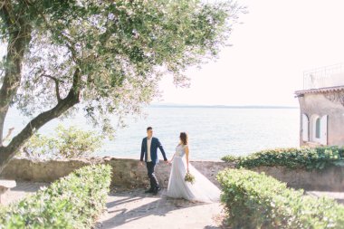 Sirmione'da yürüyüş zevk mutlu çift. Kaç Sirmione, İtalya Rocca Scaligera Bahçe yürüme düğün giysileri içinde