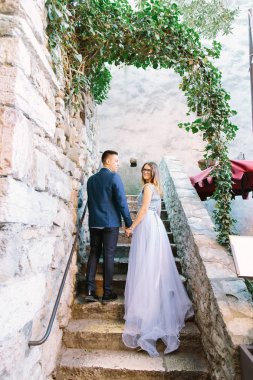 poz ve eski şehrin Sirmione, İtalya antik merdivenlerde dururken elleri bir arada tutma Mavi giysili genç güzel çift