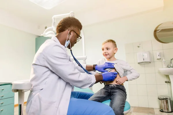 African American Doctor and child patient. Physician examines little boy by stethoscope. Medicine and children\'s therapy concept